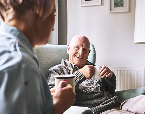 Man and woman sitting in their home, talking and enjoying a cup of coffee